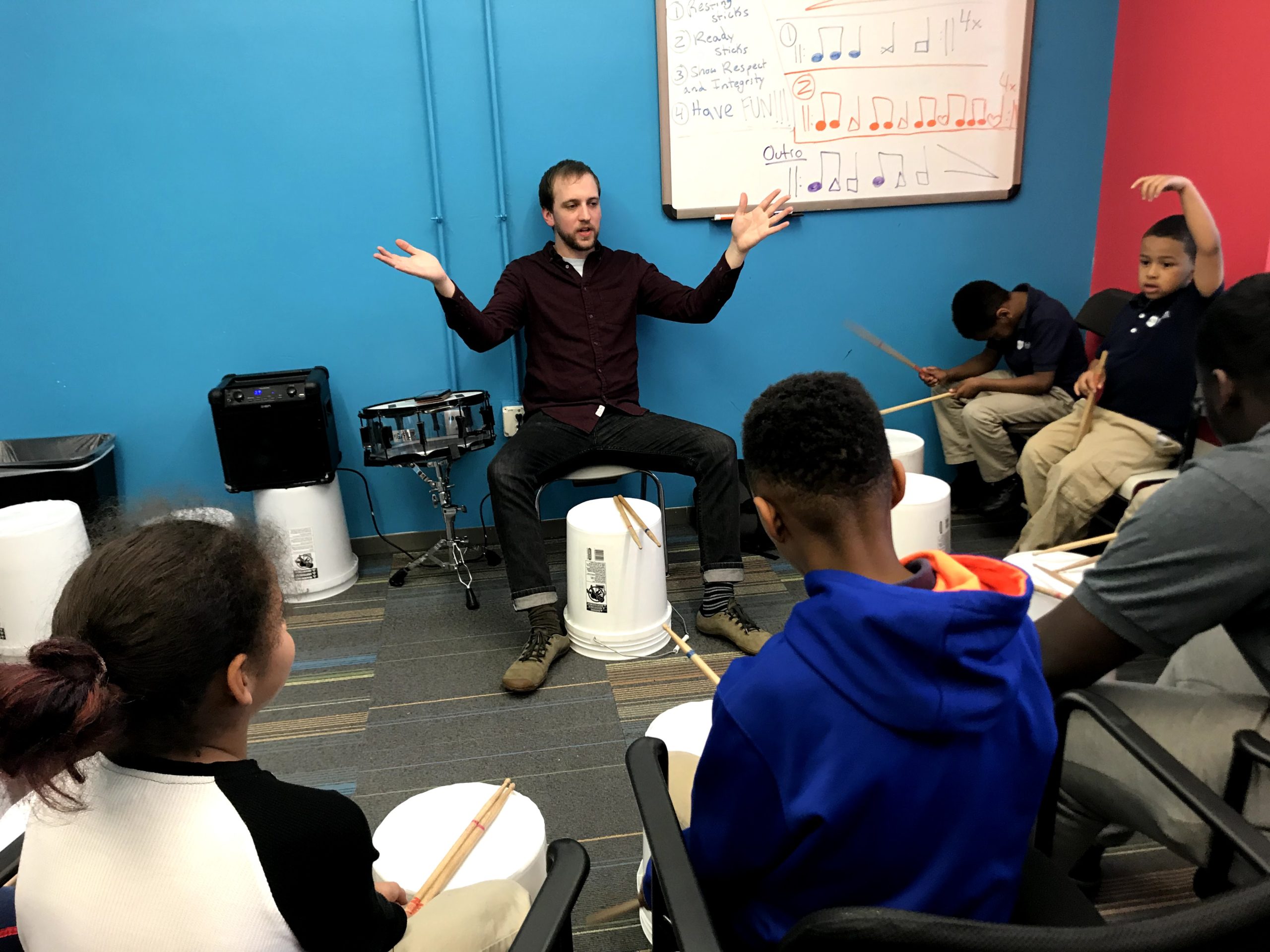 CMCB faculty member teaches bucket drumming to a group of students