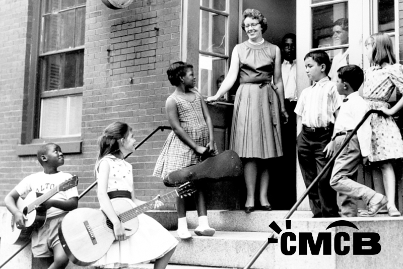 A b&w photo of the entrance to CMCB with students and a teacher