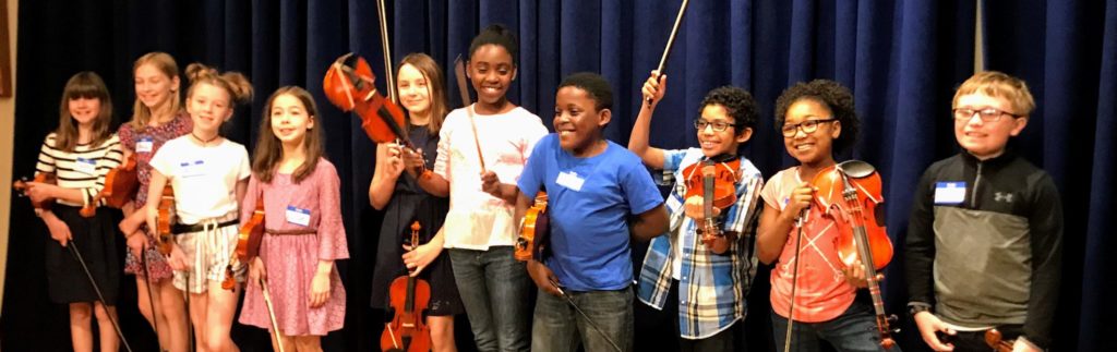 A group of young children holding violins and smiling