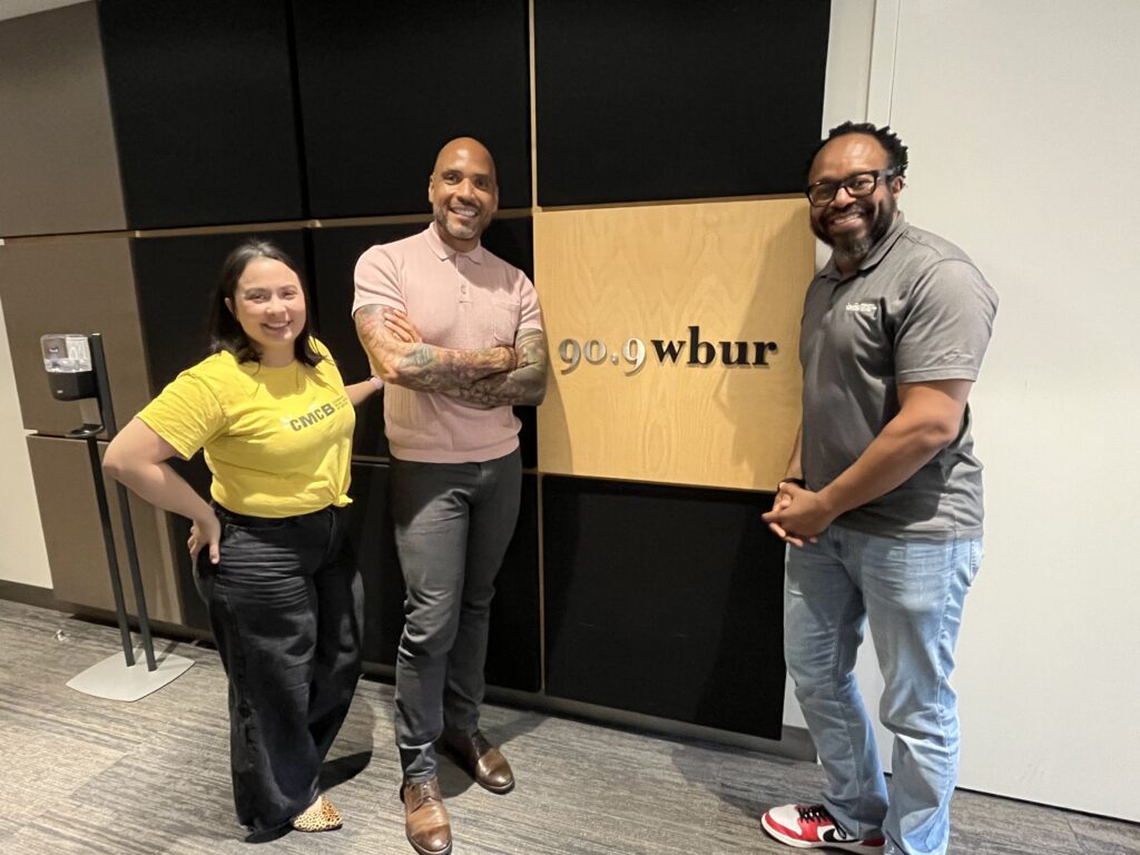 rachel, michael, and lecolion standing in front of a WBUR sign